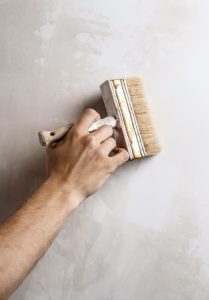 jemanden streicht die Wand mit einem Flachpinsel